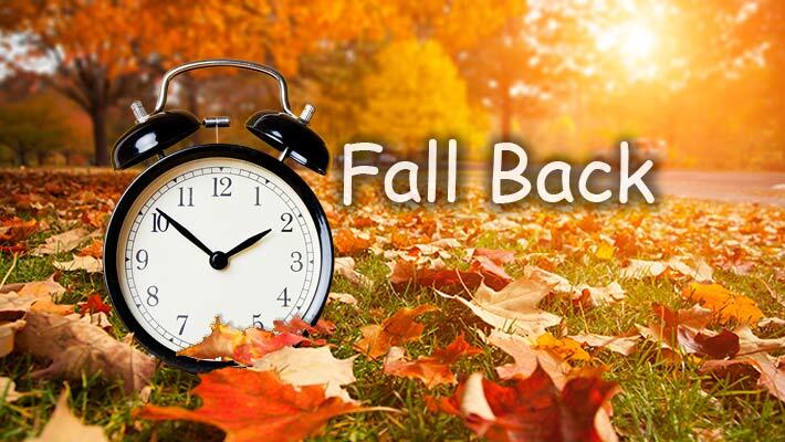Fall Back. A clock in a pile of leaves.